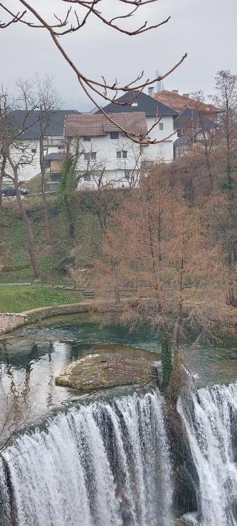 a waterfall in a field with a house in the background at Apartman Heli Meli 1 in Jajce