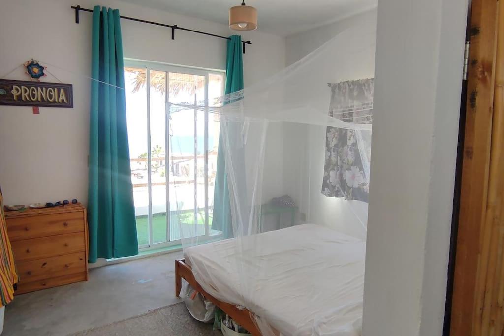 a bedroom with a bed and green curtains and a window at Casita de renta frente la playa in San Juanico