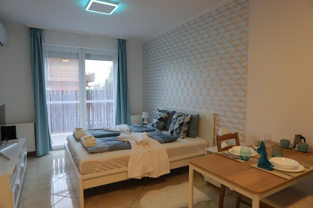 1 dormitorio con cama, mesa y comedor en Airport Luxury Apartment with Balcony + Free parking en Vecsés