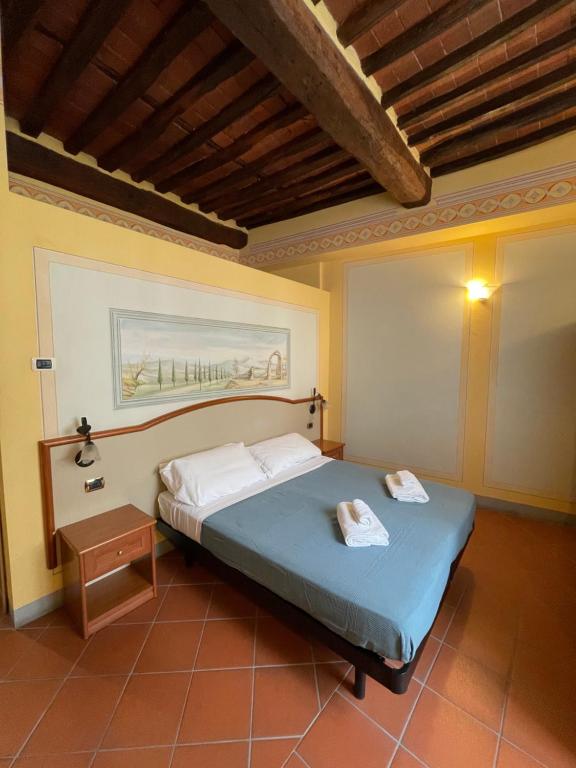 1 dormitorio con 1 cama con 2 toallas en San Pietro Tuscany Suites, en Lucca