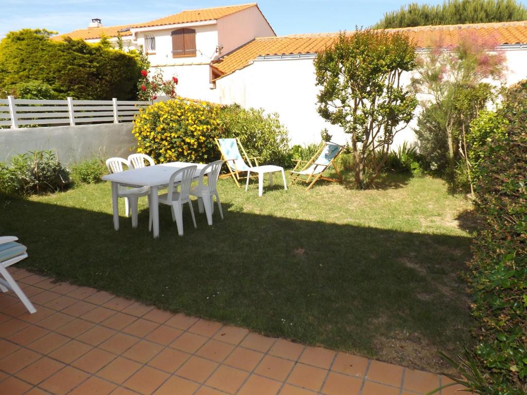 une table et des chaises dans une cour avec une pelouse dans l'établissement Maison 3 chambre quartier Boisvinet, à Saint-Gilles-Croix-de-Vie