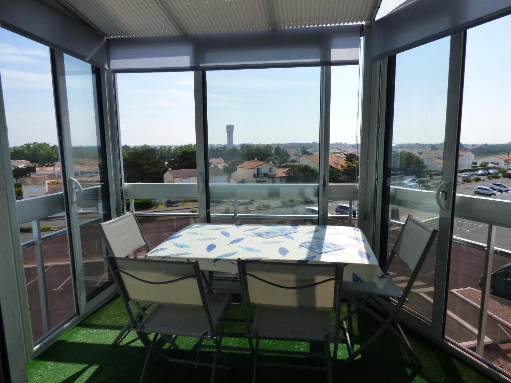 d'une table et de chaises sur un balcon avec fenêtres. dans l'établissement Le Chenal, à Saint-Gilles-Croix-de-Vie