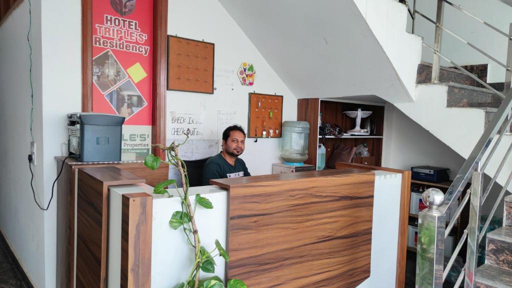 a man sitting at a counter in a room at Hotel triple s in Karnal