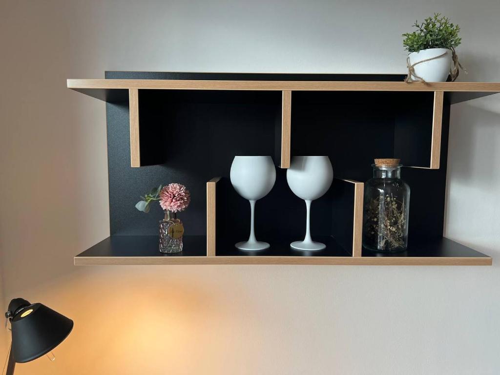 a shelf with two wine glasses and a bottle at Cozy Apartment in Spandau Rauchstr with Garden View in Berlin