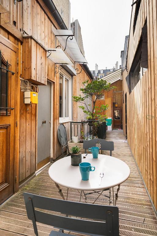 - une terrasse avec une table et des chaises sur du parquet dans l'établissement Home Sweet Home Arc de Triomphe Villa Laugier, à Paris