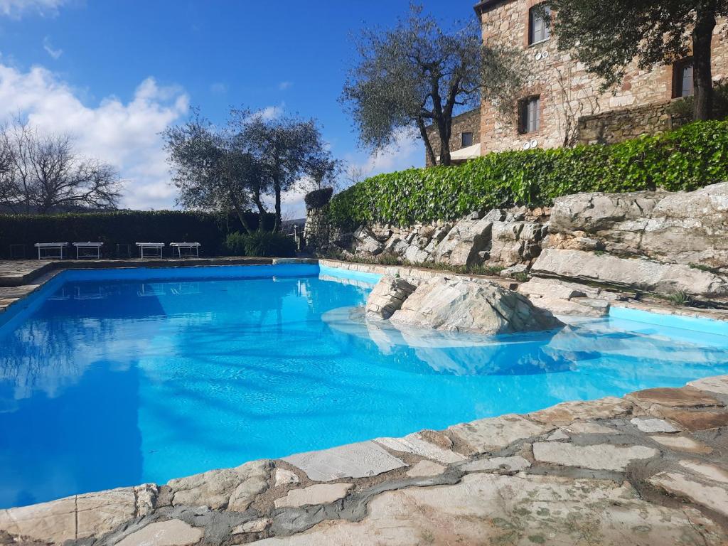 einem Pool mit blauem Wasser vor einem Gebäude in der Unterkunft Borgo Livernano - Farmhouse with pool in Radda in Chianti