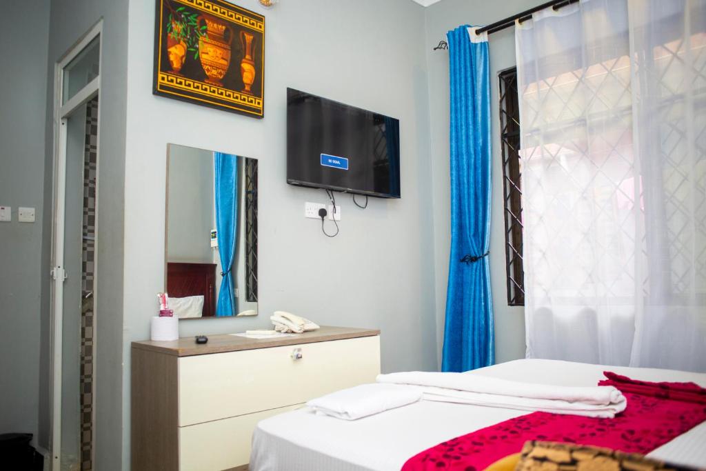 a bedroom with two beds and a tv on the wall at Magdon Executive Lodge in Dar es Salaam