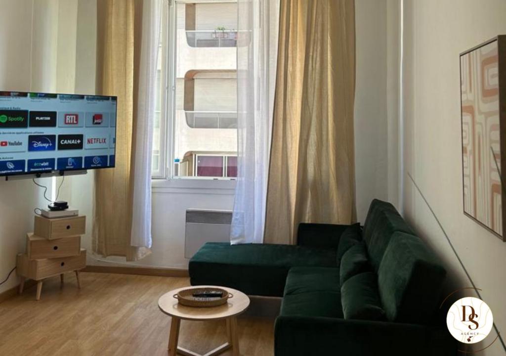 a living room with a green couch and a television at Havre de paix spacieux près du Prado et du Stade Vélodrome in Marseille