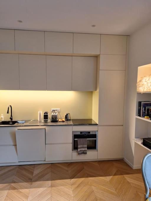 une cuisine avec des armoires blanches et un évier dans l'établissement Appartement 35 m² dans le Marais, à Paris