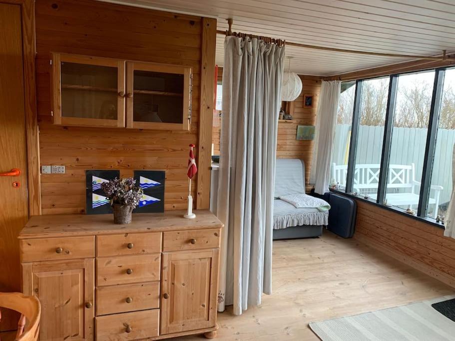 a room with a dresser and a bedroom in a cabin at Bo i vandkanten på Avernakø in Fåborg