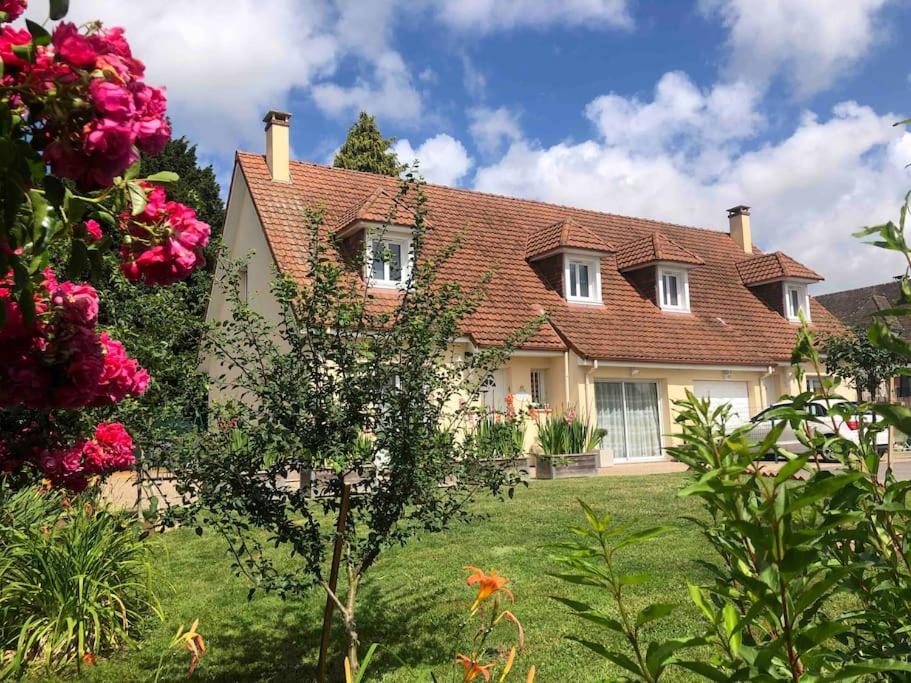 ein großes Haus mit einem Hof mit rosa Blumen in der Unterkunft Maison accueillante en Normandie in Montivilliers