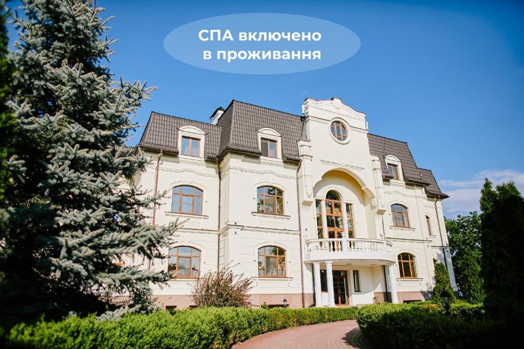 a large white house with a tree in front of it at Koncha Zaspa Park by HeyDay in Kozin