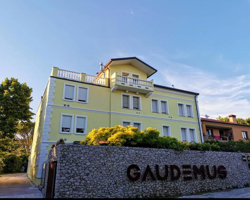 a yellow building with a balcony on top of it at Locanda Gaudemus Boutique Hotel in Sistiana