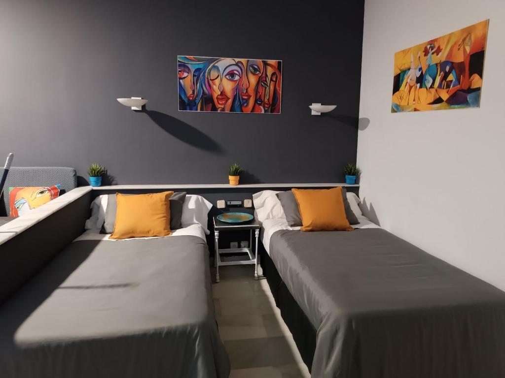 マルベーリャにあるApartamento en Puerto Banúsのベッド2台が備わる客室で、壁には絵画が飾られています。