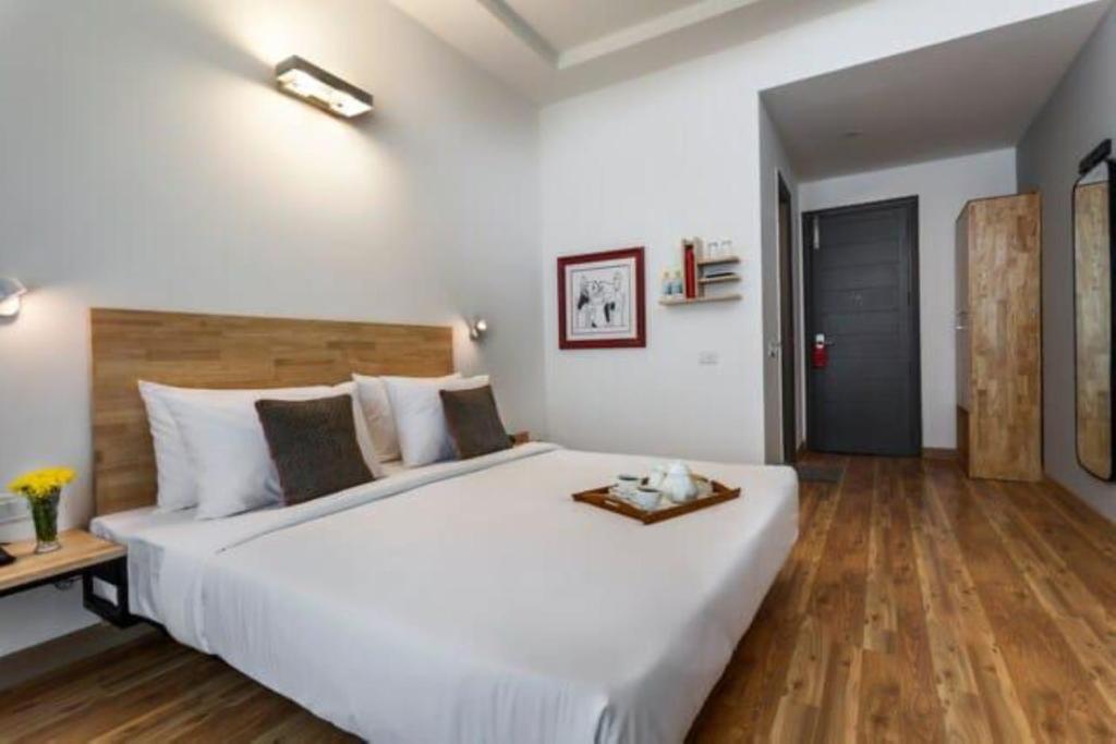 Hotel Majestic JPM - East Of Kailash في نيودلهي: غرفة نوم بسرير ابيض كبير وارضية خشبية