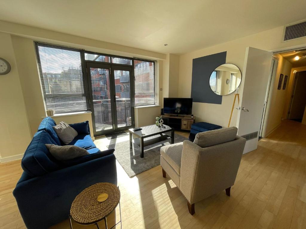 uma sala de estar com um sofá azul e uma cadeira em Modern 2 BDR Flat in Nottingham City Centre with free parking em Nottingham