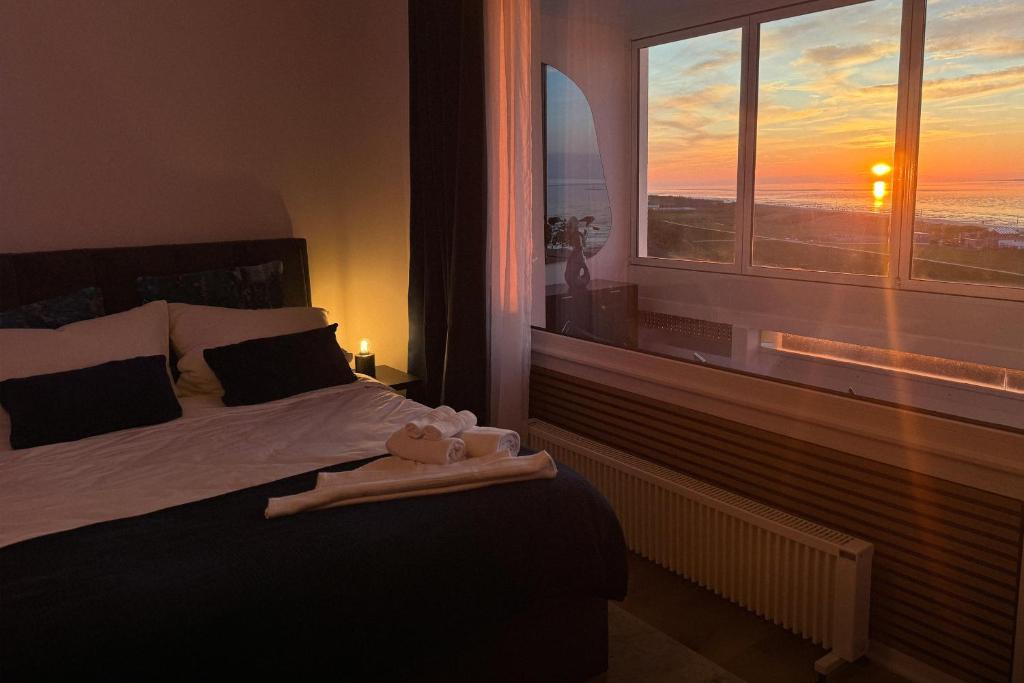 um quarto com uma cama e uma janela com um pôr-do-sol em CuxHeaven modernes Studio-Apartment direkt am Meer mit Pool, Sauna und Massage em Cuxhaven