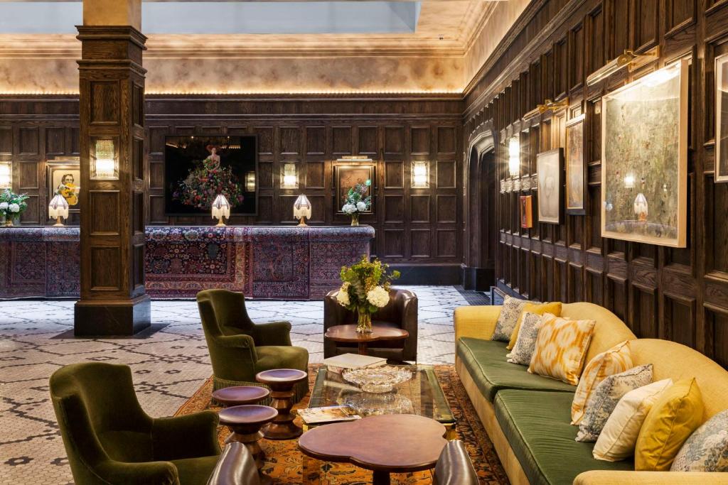 a lobby with a green couch and chairs at The Beekman, A Thompson Hotel, by Hyatt in New York