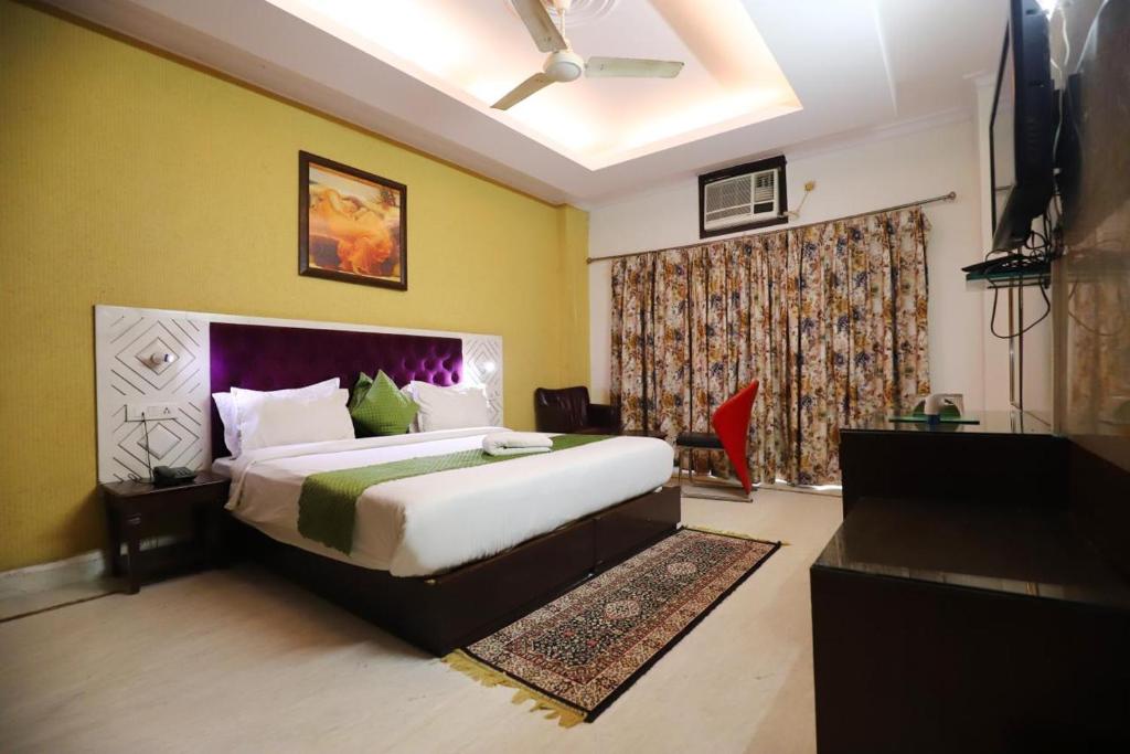 een slaapkamer met een groot bed en een televisie bij Vagmi Inn in Gurgaon