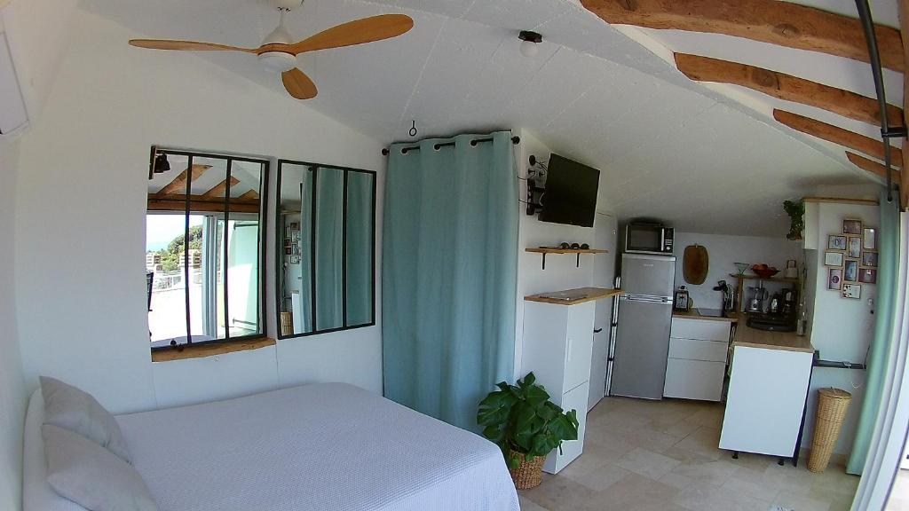 une chambre avec un lit et un ventilateur de plafond dans l'établissement Studio le Nid, vue mer, village et collines avec terrasse, à Bormes-les-Mimosas