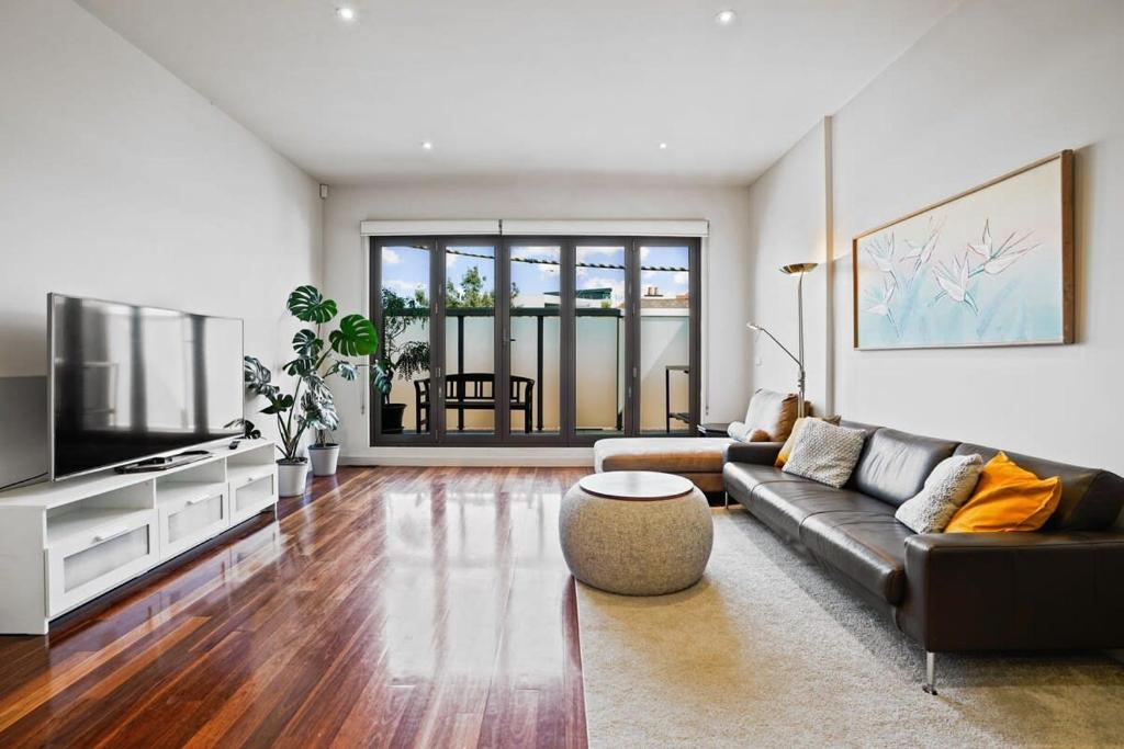 a living room with a couch and a tv at Trendy 3 Level Retreat at North Melbourne with parking in Melbourne