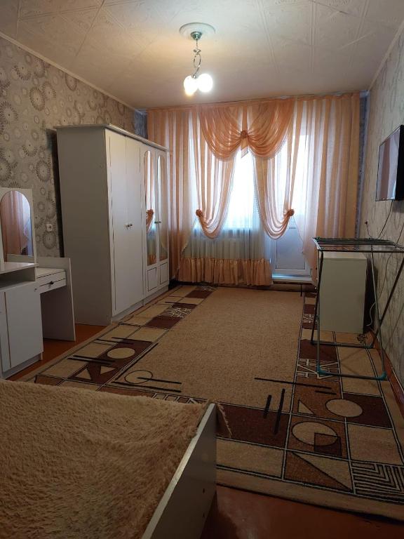 una sala de estar vacía con ventana y alfombra en Квартира, en Pavlodar