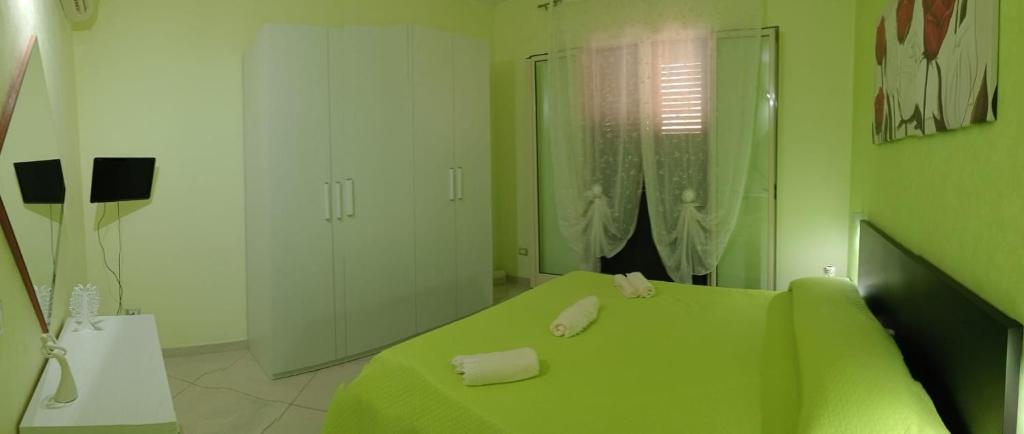 Habitación verde con 1 cama con toallas. en Casa vacanze valentino, en Avola