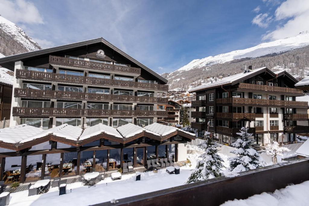 a lodge in the snow with snow covered buildings at Mirabeau Etoile in Zermatt