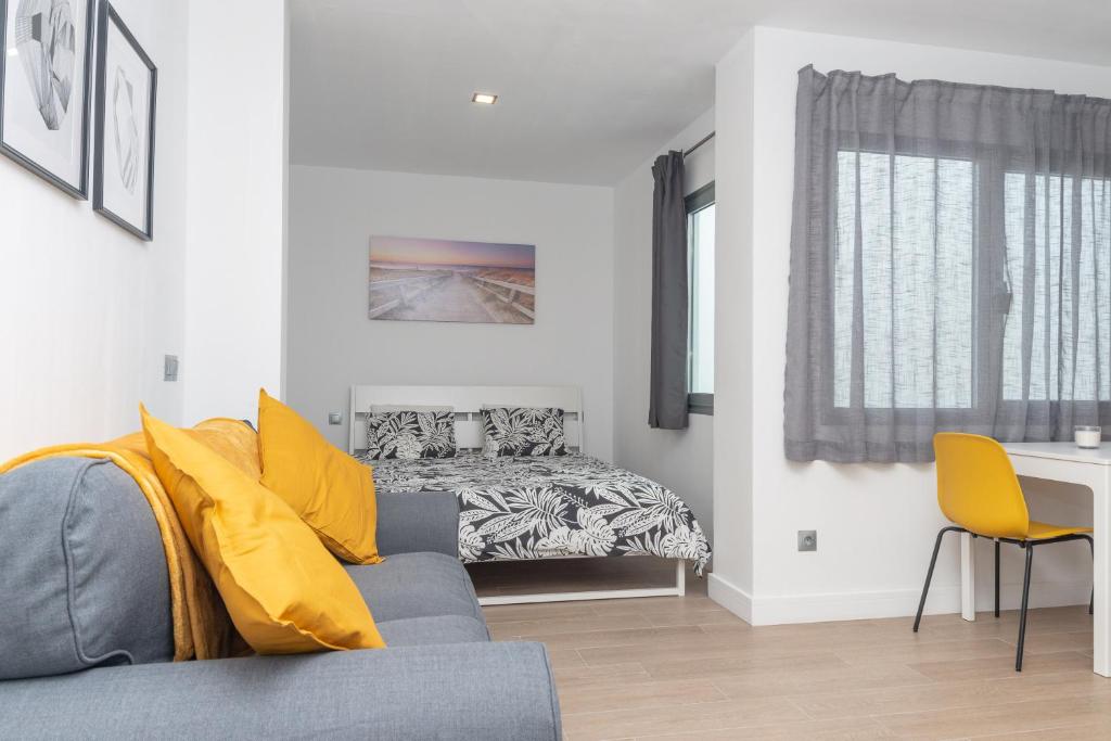 1 dormitorio con 1 cama y 1 sofá con almohadas amarillas en Lightbooking Canteras Beach Studio, en Las Palmas de Gran Canaria