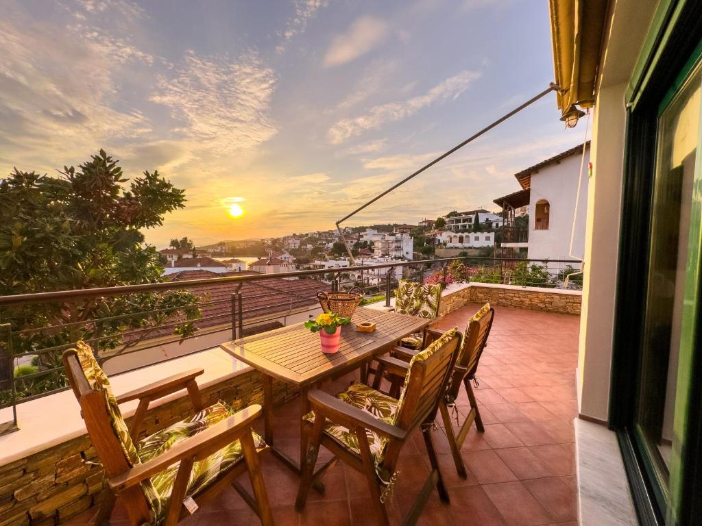 een tafel en stoelen op een balkon met een zonsondergang bij Blue Bay Villa in Volos