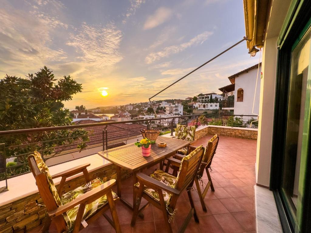 a table and chairs on a balcony with a sunset at Blue Bay Villa in Volos
