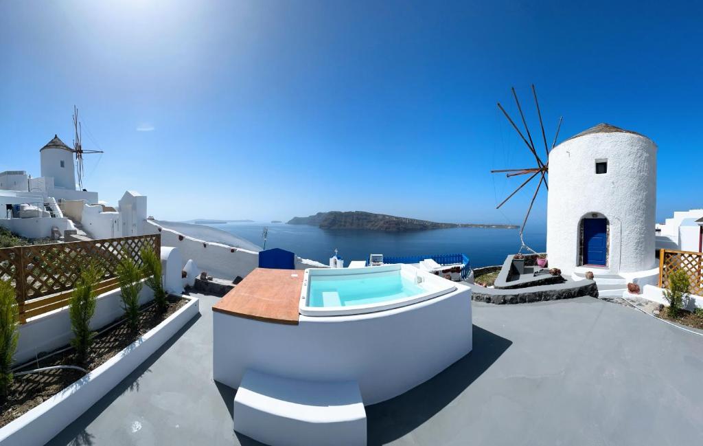 a villa with a swimming pool and a windmill at Lioyerma Windmill Villa With Outdoor Hot Tub in Oia