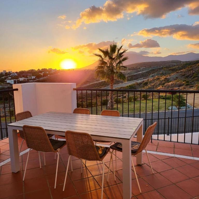 a table and chairs on a balcony with a sunset at Paraiso Pueblo in Benahavís