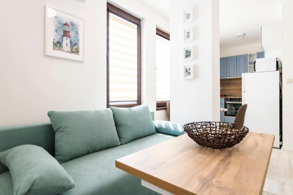 a living room with a green couch and a wooden table at Summer Vibes Apartment in Burgas