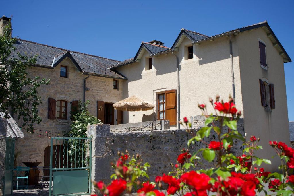 uma casa com flores vermelhas em frente em Aux coeurs du Méjean 