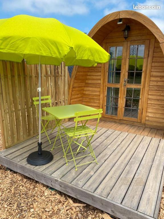 une table et des chaises vertes sous un parasol sur une terrasse dans l'établissement Les Hébergements Insolites Catalans, à Saint-André