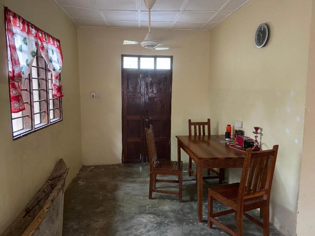 een eetkamer met een tafel en stoelen en een deur bij Village Hostel in Nungwi