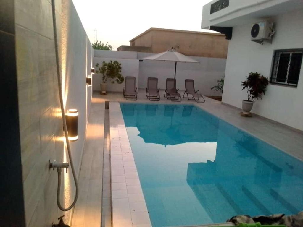 a swimming pool with chairs and an umbrella at Villa Fama in Mbour