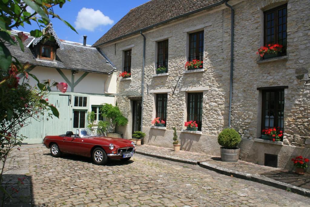 um carro vermelho estacionado em frente a um edifício em Au Relais de Chaussy em Chaussy