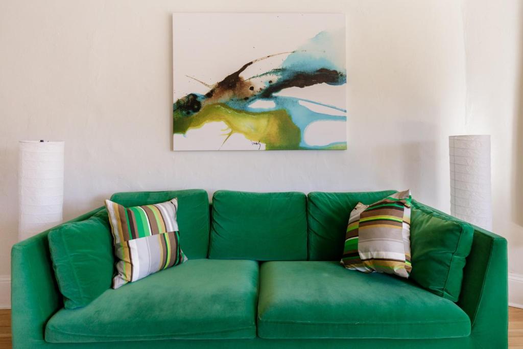 a green couch in a living room with a painting at Dog-friendly Downton Annie #4 in Asheville