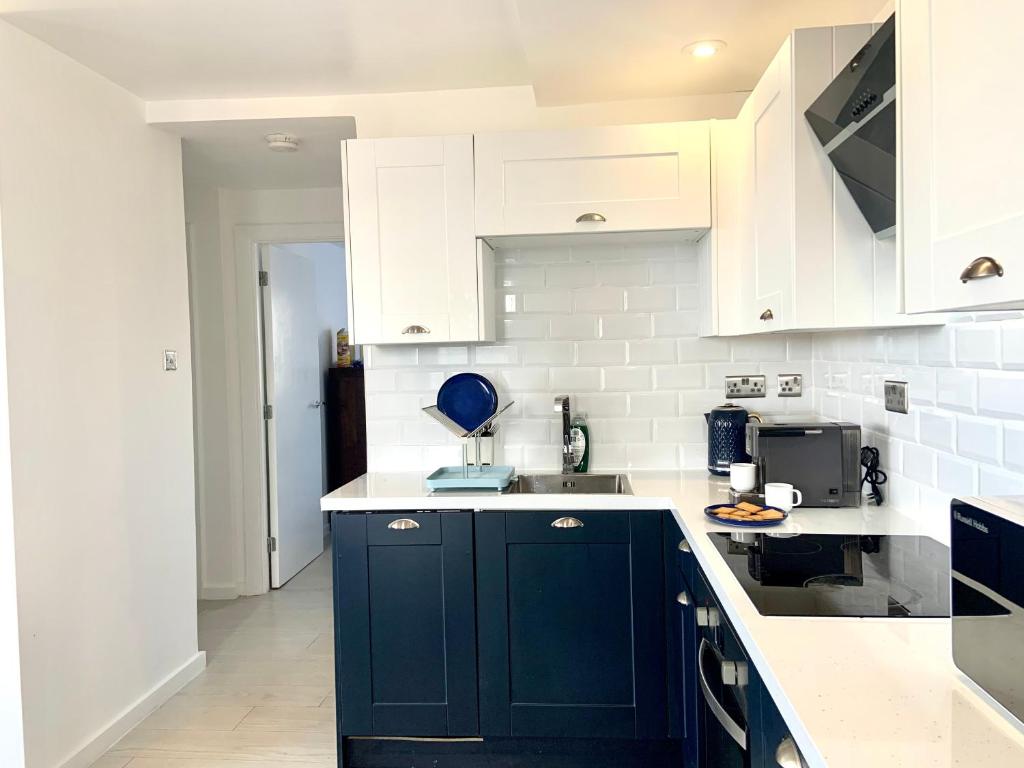 a kitchen with dark blue cabinets and white appliances at Elegant two bedroom city central apartment in Leeds