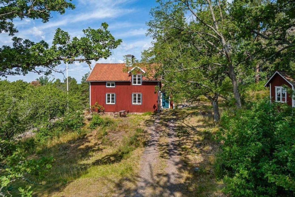 una casa roja en medio de un camino de tierra en Charmigt torp på höjden, en Gamleby