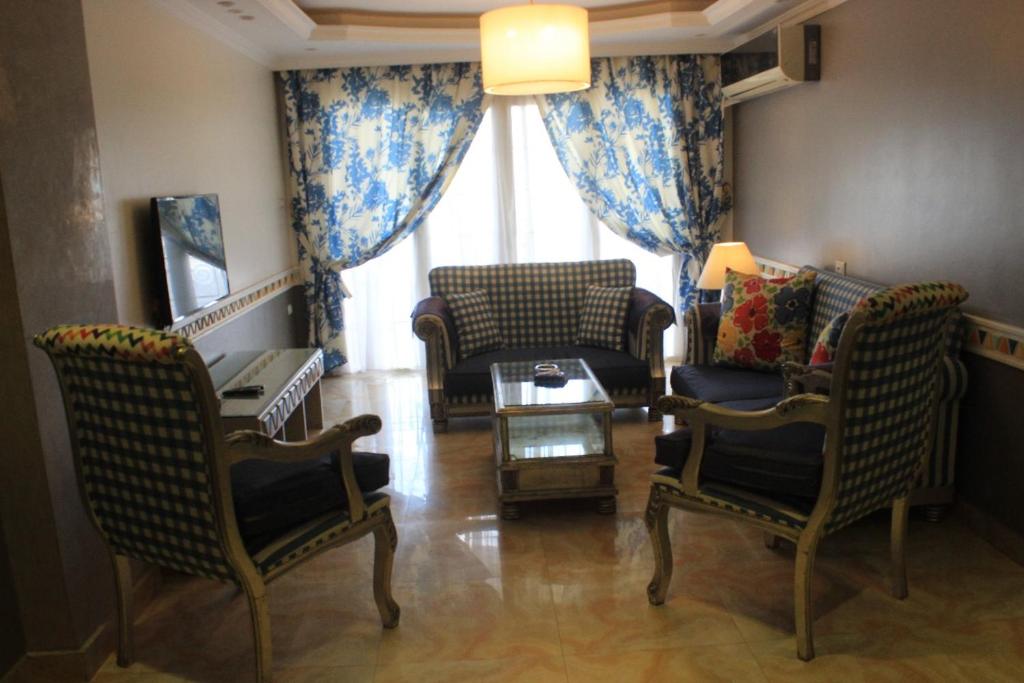 un soggiorno con sedie, tavolo e finestra di ALMADIAFAH APARTMENT - المضيفة للوحدات الفندقيه a Mansoura