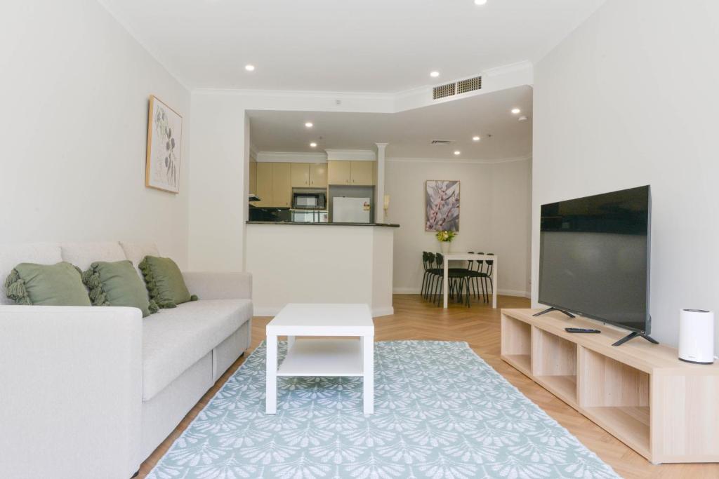 a living room with a white couch and a flat screen tv at Great Location! Darling Harbour Superb 2BR Apt in Sydney