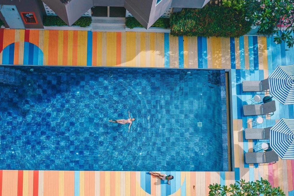 a man swimming in a swimming pool with a person in it at Sila at Hua Hin Serviced Apartment & Hotel in Hua Hin