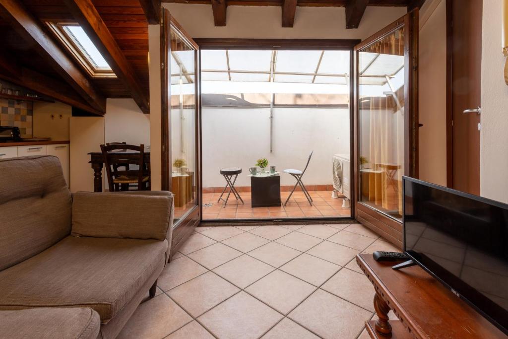een woonkamer met een bank en een televisie bij Dante's Skyview - Appartamento mansarda Novara STAZIONE in Novara