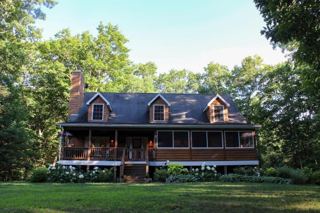 une grande maison en bois avec une terrasse couverte sur une pelouse dans l'établissement Discover Spring Haven in a Cozy Cabin Catskills, à Palenville