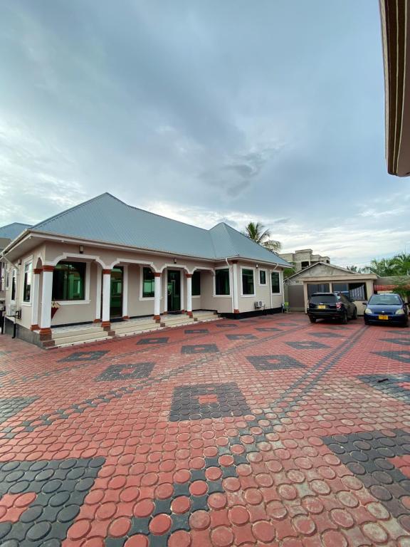 un bâtiment avec des voitures garées dans un parking dans l'établissement Magdon Lodge, à Dar es Salaam