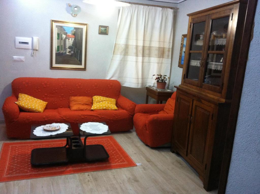 a living room with a red couch and a chair at S'apposentu in Aritzo