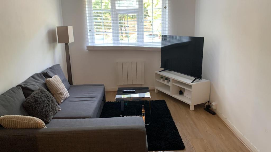 uma sala de estar com um sofá e uma televisão de ecrã plano em 1 bed Flat Service Apartment Beckenham em Beckenham